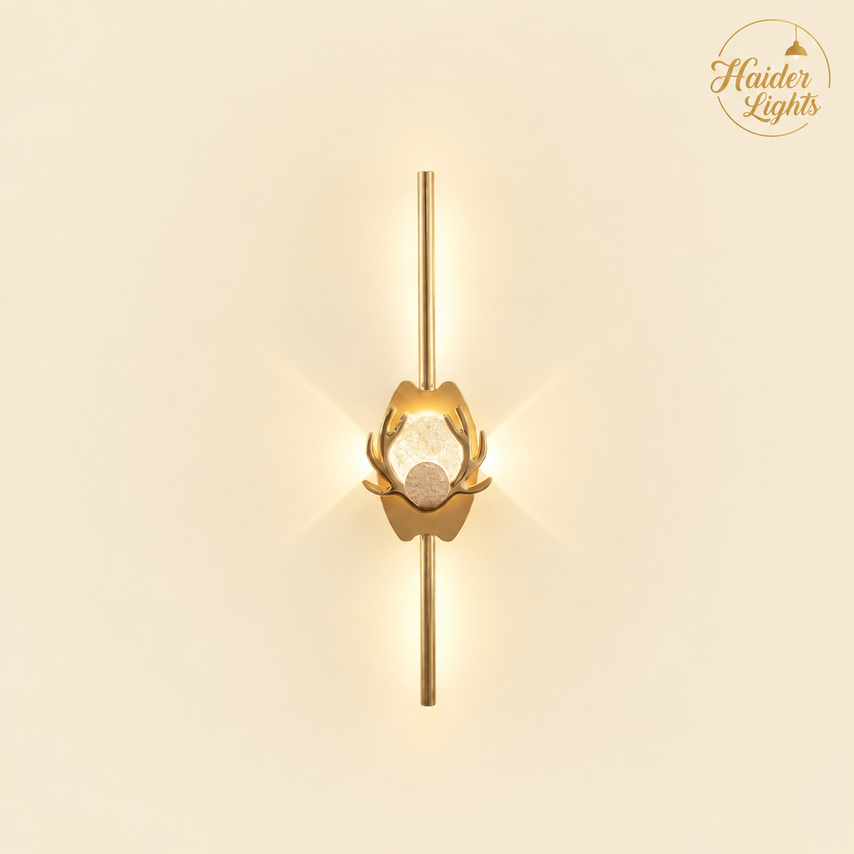 A modern gold wall sconce with a vertical rod, a central lotus-like gold frame, and a clear faceted crystal prisma, shown against a warm cream background with a brand logo in the top right.