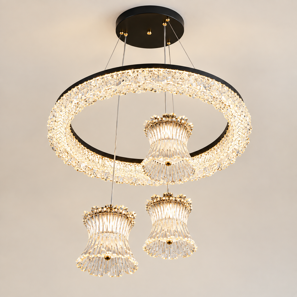 Modern three-light chandelier with a large circular crystal ring and two hanging bell-shaped crystal shades, suspended from a black ceiling canopy against a plain light background.