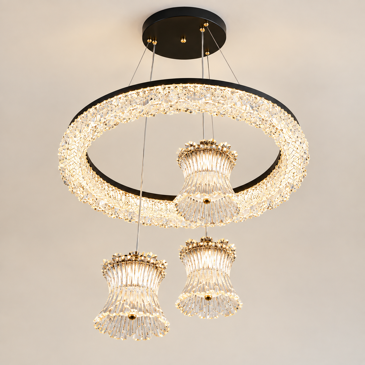 Modern three-light chandelier with a large circular crystal ring and two hanging bell-shaped crystal shades, suspended from a black ceiling canopy against a plain light background.